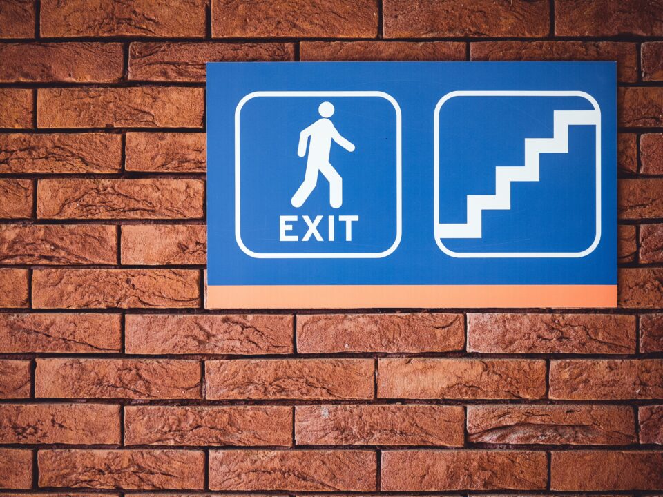 blue and white exit signage mounted on brown brick wall