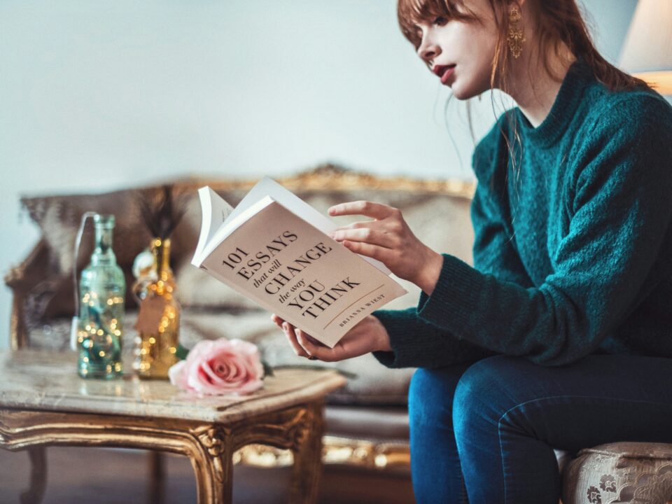 woman sitting down near table reading 101 Essays book