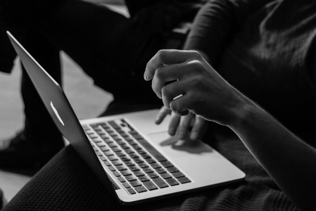 Current image: grayscale photo of person using MacBook